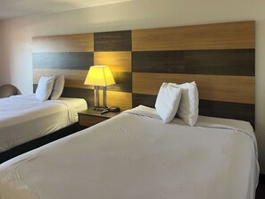 A hotel room with two beds, a nightstand with a lamp, and a clock. - Motel 6 Cross Lanes, WV - Goff Mountain Rd (Cross Lanes)