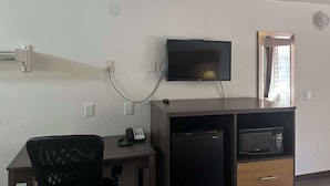 A room with a desk, a television mounted on the wall, a microwave, and a refrigerator. - Motel 6 Cross Lanes, WV - Goff Mountain Rd (Cross Lanes)