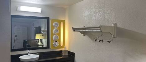 A bathroom with a sink, mirror, towel rack, and a small table.