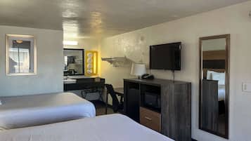 A hotel room with two beds, a desk with a computer, a TV, and a mirror.