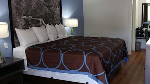 A hotel room with a large bed, two bedside lamps, a nightstand, and a painting on the wall.