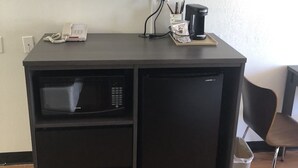 A compact kitchenette with a microwave, refrigerator, and a flat-screen TV mounted above the counter.
