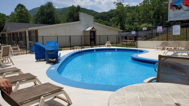 A swimming pool with lounge chairs and a covered seating area.