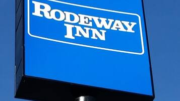 Un letrero azul con el texto 'Rodeway Inn' sobre un cielo despejado.