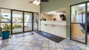 A reception area with a reception desk, a ceiling fan, a potted plant, and a view of the outside through glass doors. - Rodeway Inn Near Hall of Fame (North Canton)
