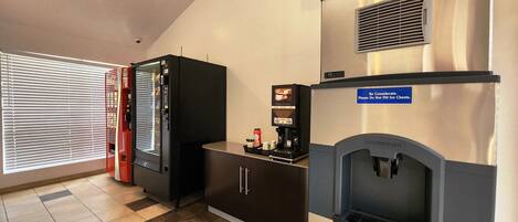 Een kitchenette met een koffiezetapparaat, een minikoelkast en een ingebouwde ijsmachine.