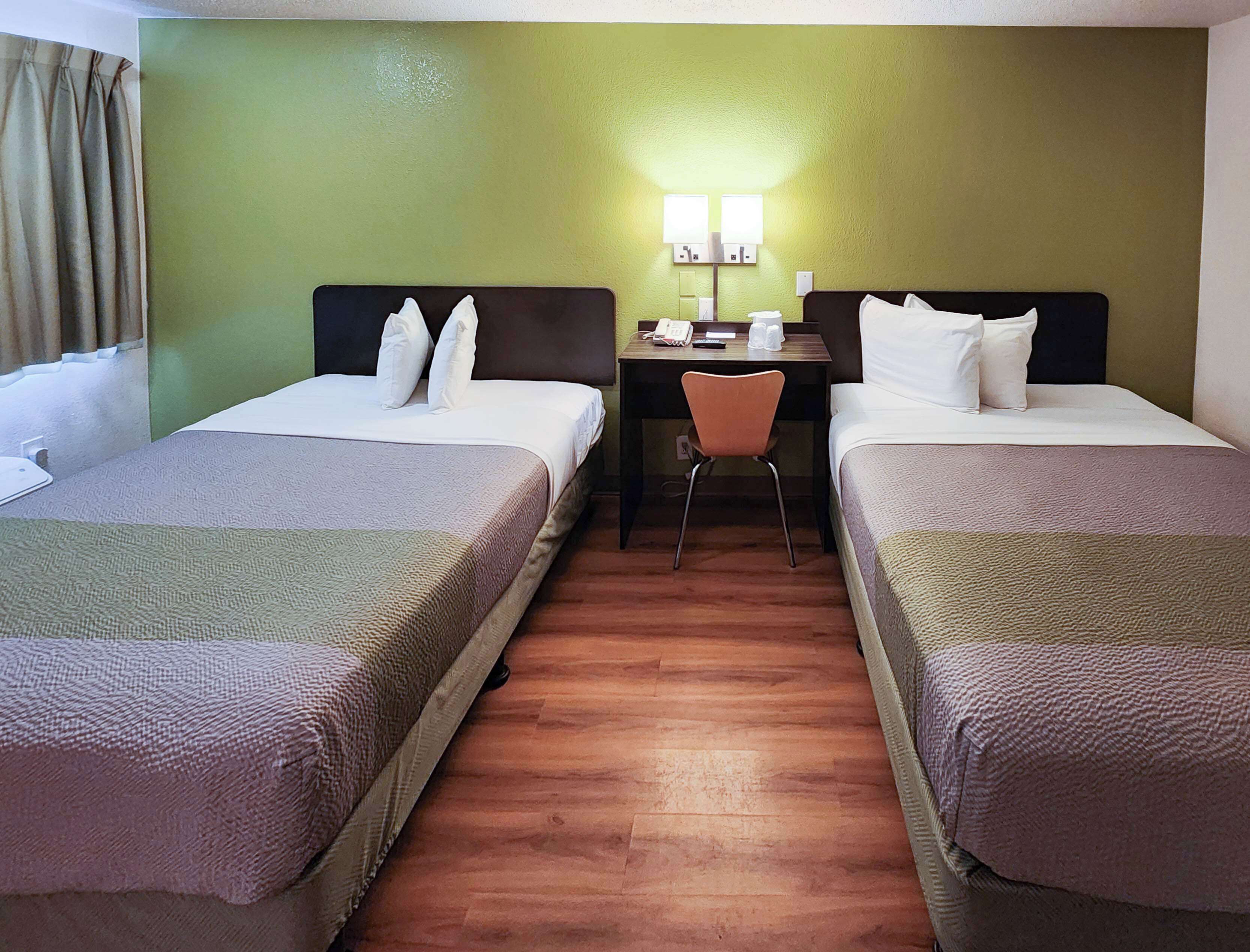 A hotel room with two beds, a desk, and a chair.