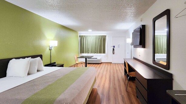 Habitació d'hotel amb llit, escriptori, cadira, televisió i mirall.