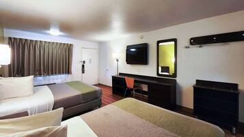 A hotel room with two beds, a desk, a chair, a TV, a mirror, and a coat rack.
