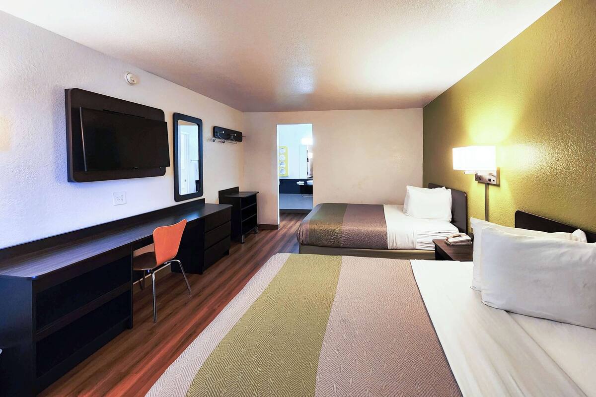 A hotel room with a bed, a desk, a chair, a TV, and a lamp.
