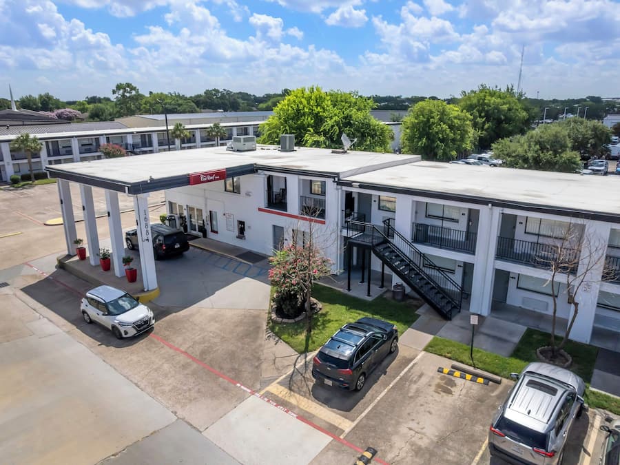 A motel with a gas station, multiple parking spaces, and a small garden area.