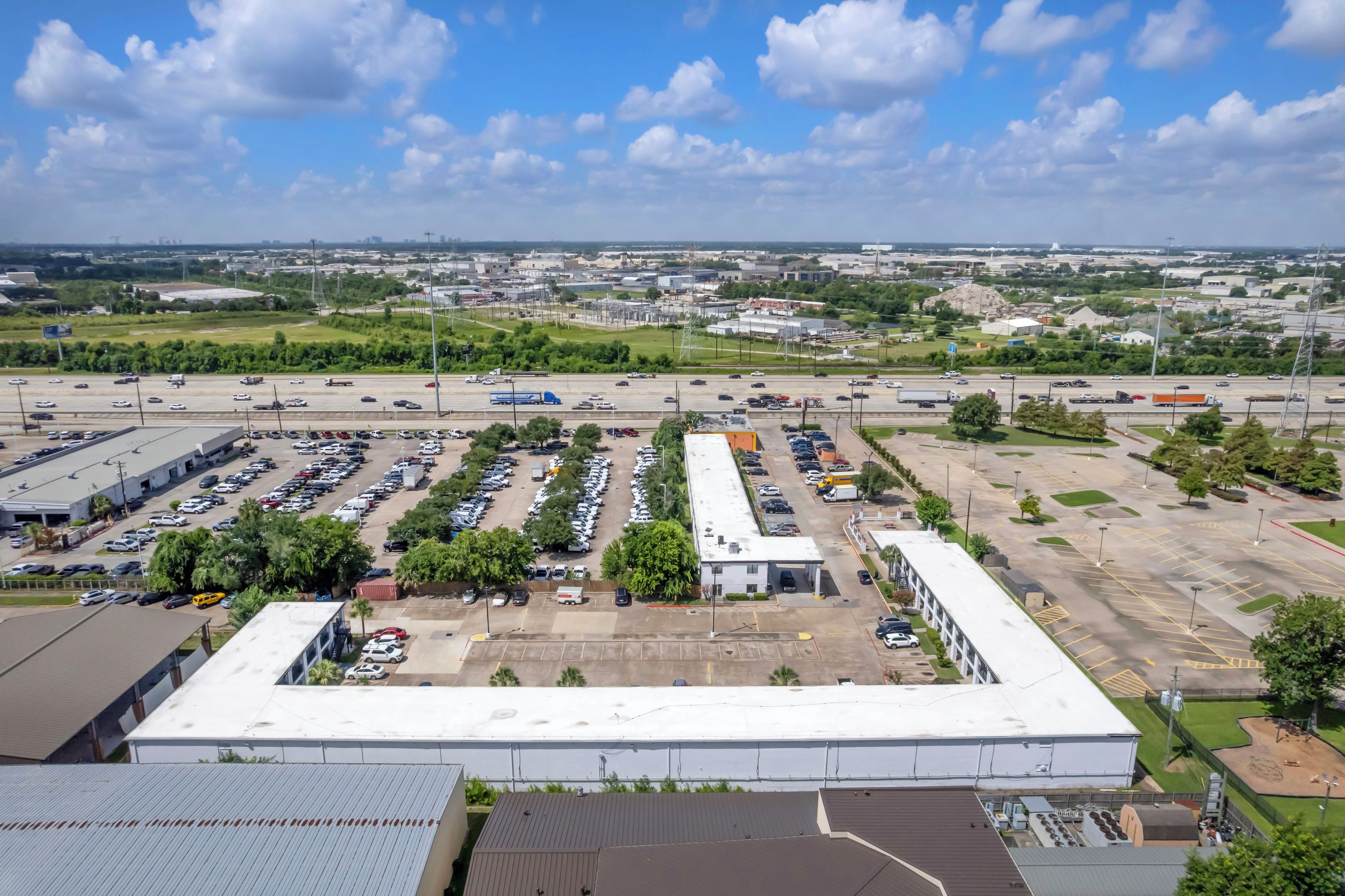 Ein großer Parkplatz mit mehreren Reihen geparkter Autos und einigen Gebäuden im Hintergrund.