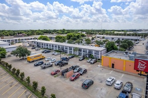 A parking lot with multiple vehicles, a building with a Red Roof Inn sign, and a large truck. - Red Roof Inn Houston – Jersey Village (Houston)