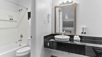 Un baño moderno con inodoro blanco, lavabo negro y espejo con iluminación.