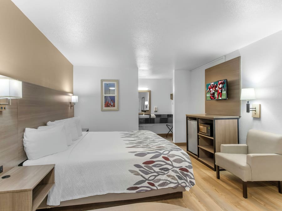 A hotel room with a bed, a desk, a chair, and a television.