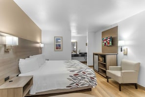 Una habitación de hotel con cama, escritorio, silla y televisor.