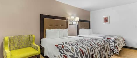 A hotel room with a bed, a chair, and a wall-mounted light fixture.