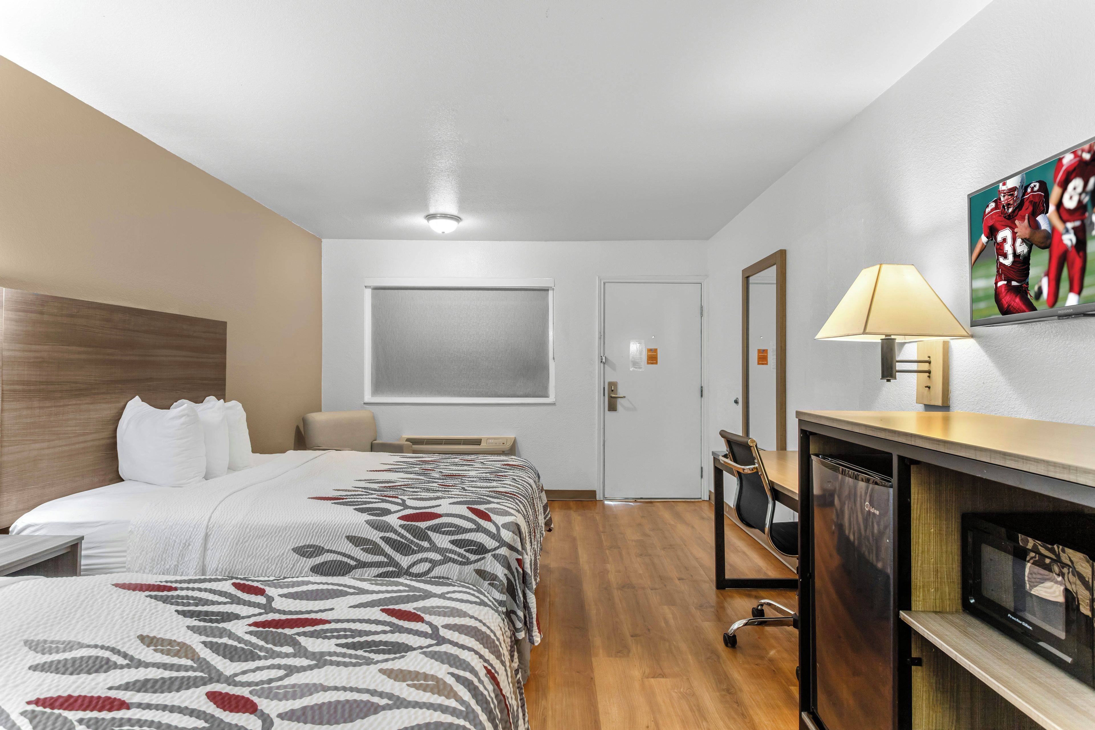 A hotel room with a bed, bedside table, lamp, and a television.