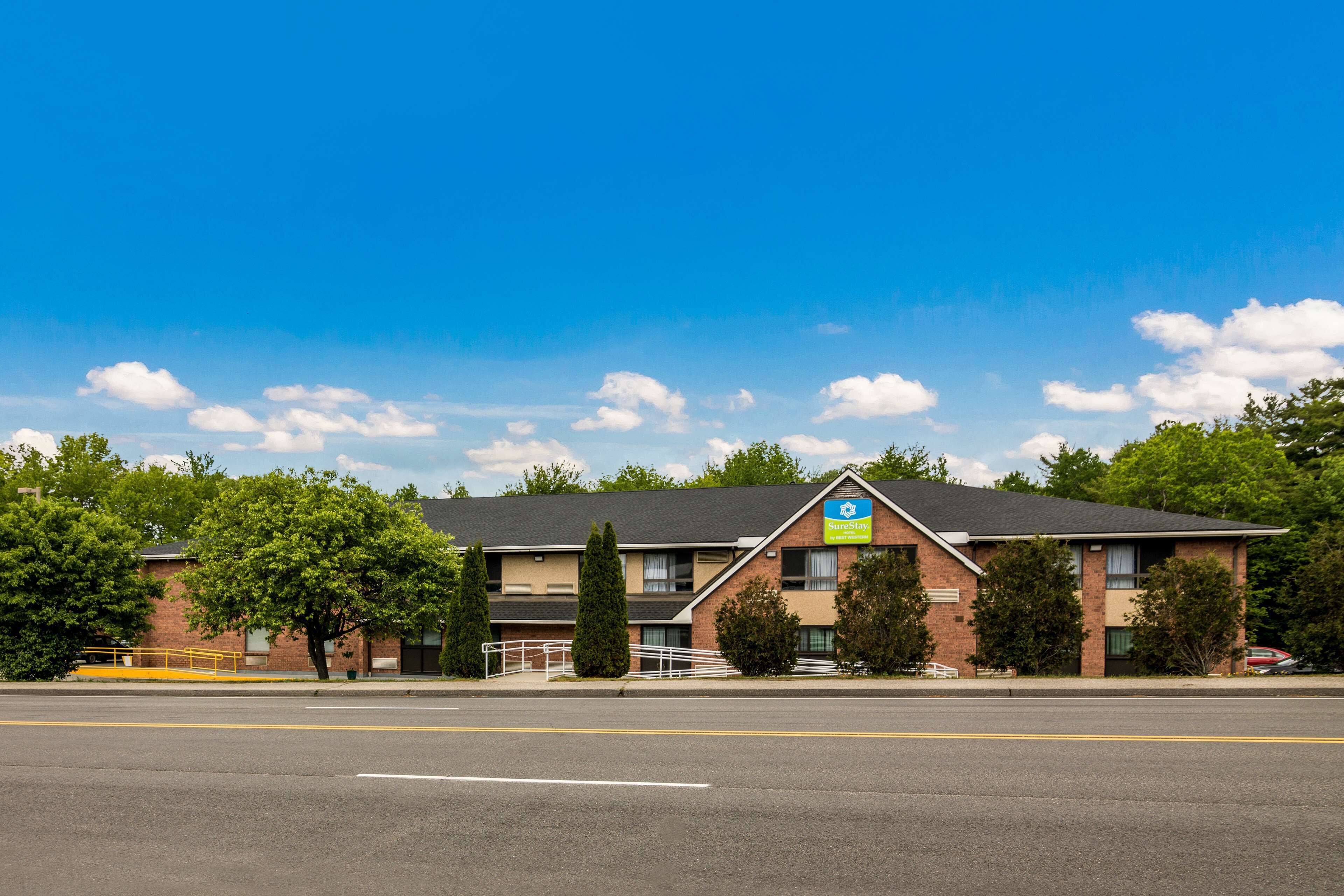 A hotel with a brick facade, a blue sign, and a parking lot.