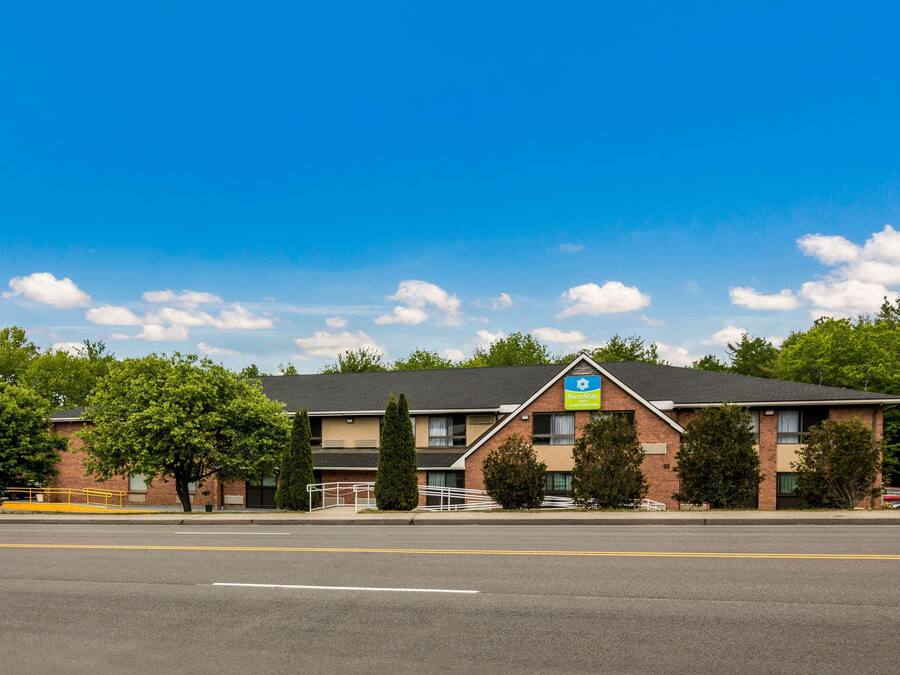 A hotel with a brick facade, a blue sign, and a parking lot.