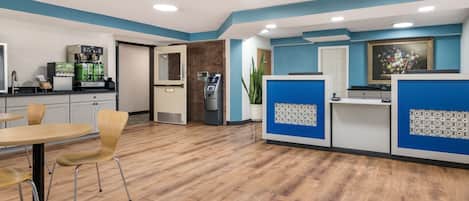 A modern reception area with a coffee machine, seating, and a plant.