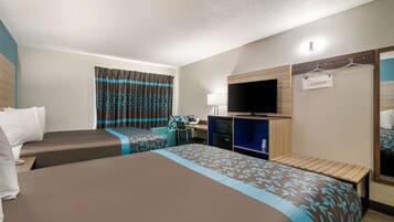 Ein Hotelzimmer mit zwei Betten, einem Schreibtisch mit Computer, einem Fernseher und einem Wäschezeichen.