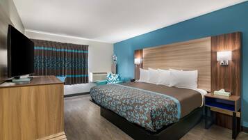 A hotel room with a large bed, a desk, a television, and a window with curtains.