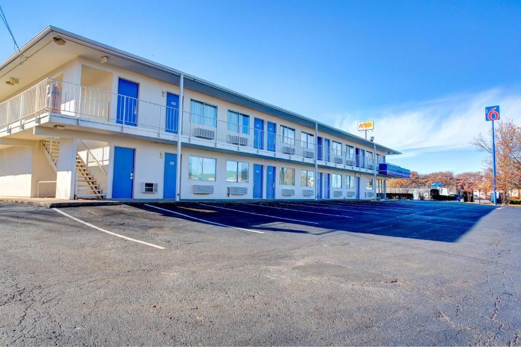 Un motel con una struttura a due piani, un parcheggio e cielo sereno.