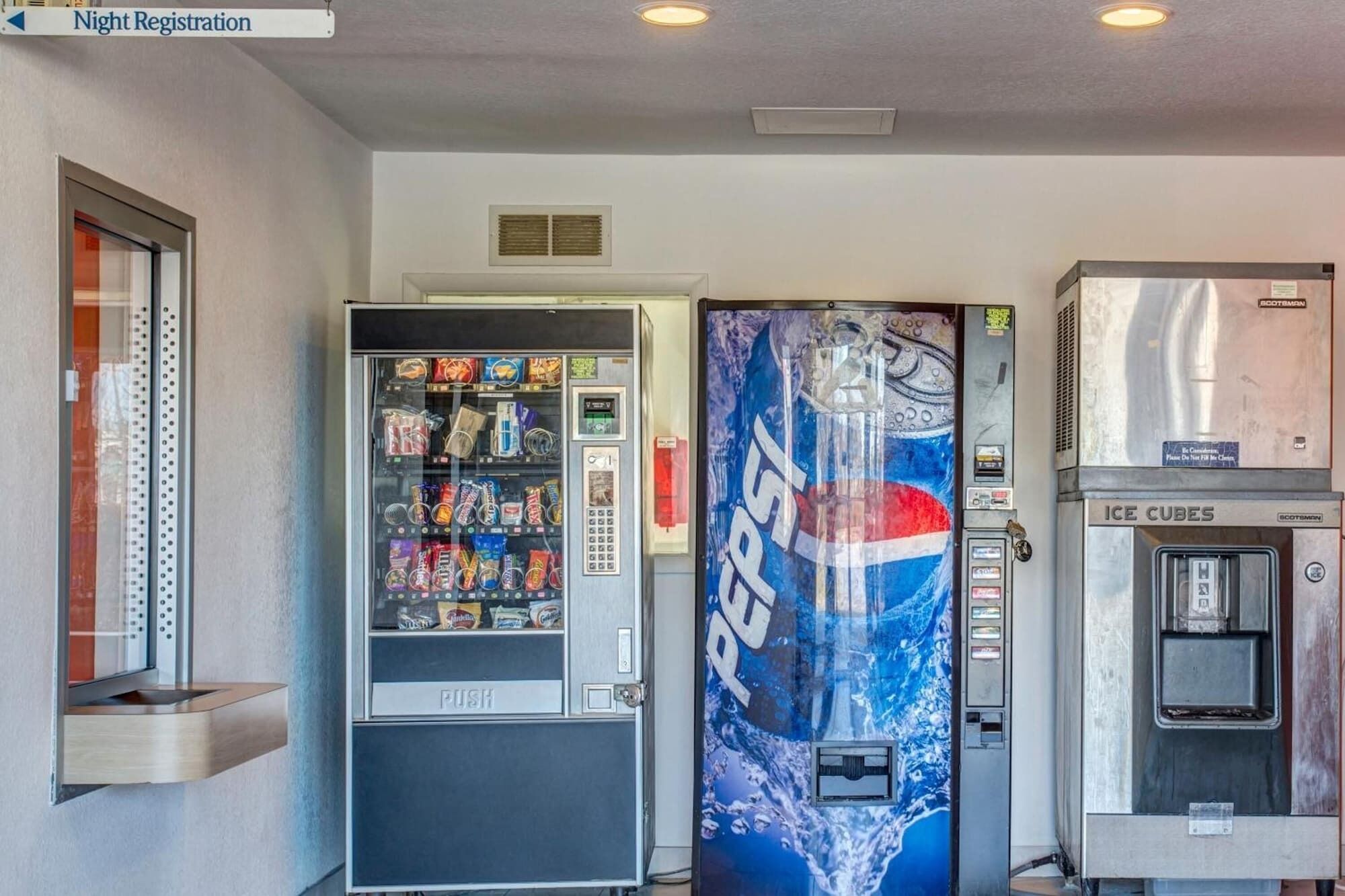 A vending machine area with a Pepsi refrigerator, an ice dispenser, and a night registration sign.
