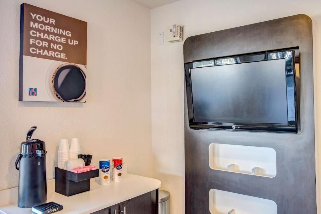 Ein Hotelzimmer mit einer Kaffeestation, einem an der Wand montierten Fernseher und einem Schild über der Kaffeestation.