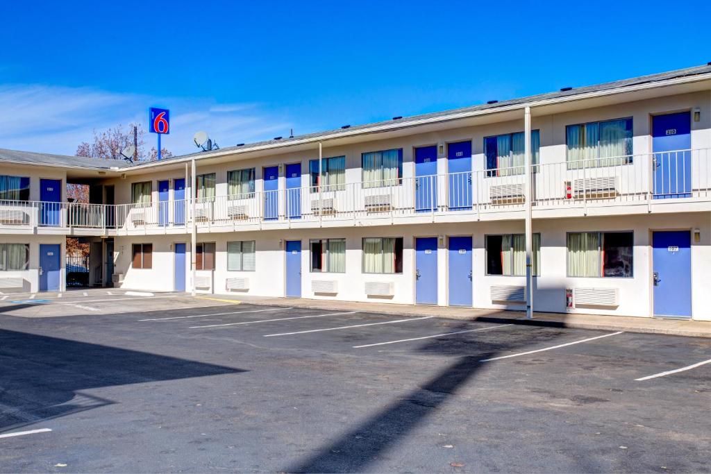 A motel with a two-story structure, multiple rooms with blue doors, and a parking lot.