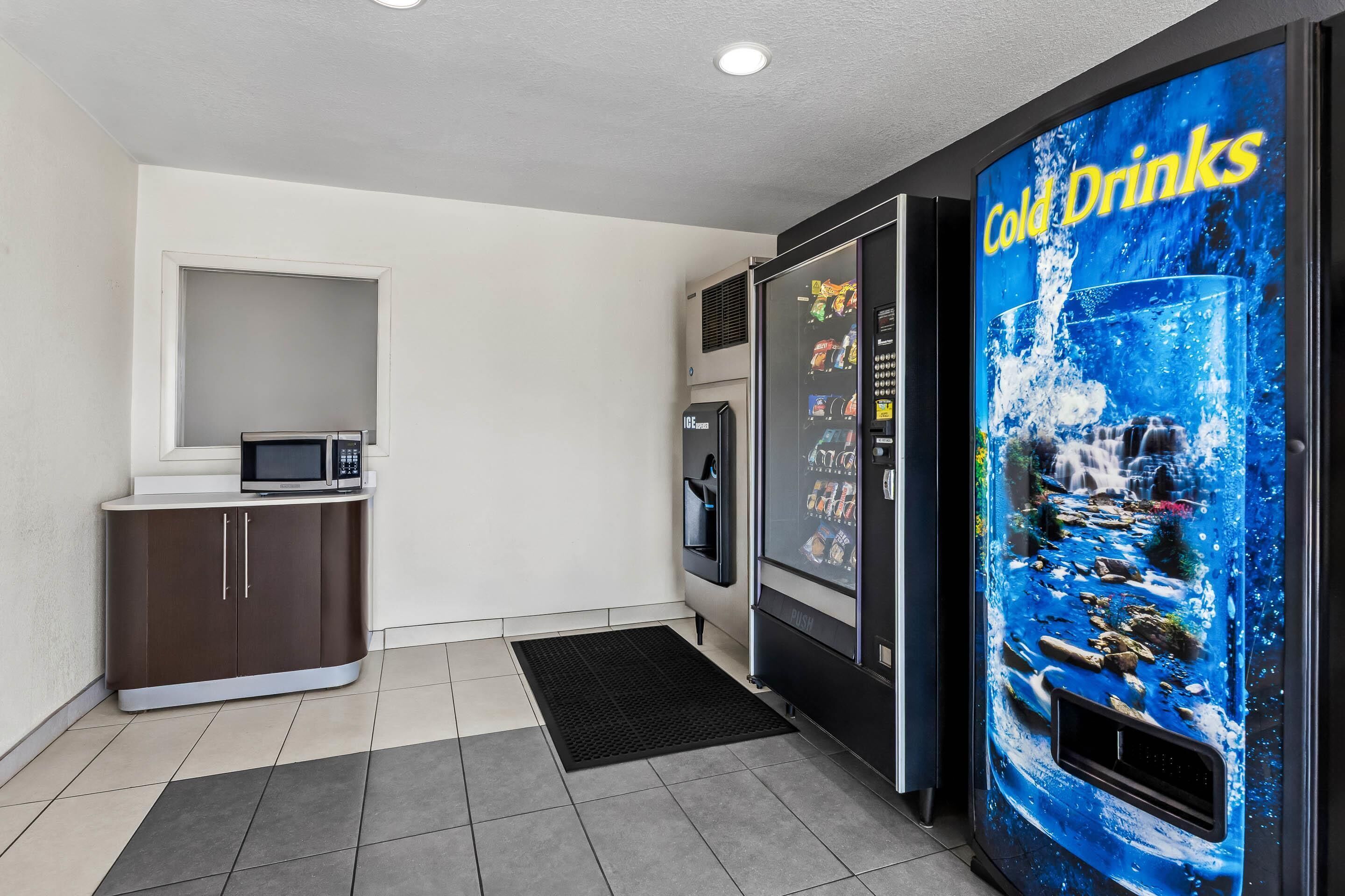 A kitchenette with a microwave, refrigerator, and a vending machine labeled "Cold Drinks".