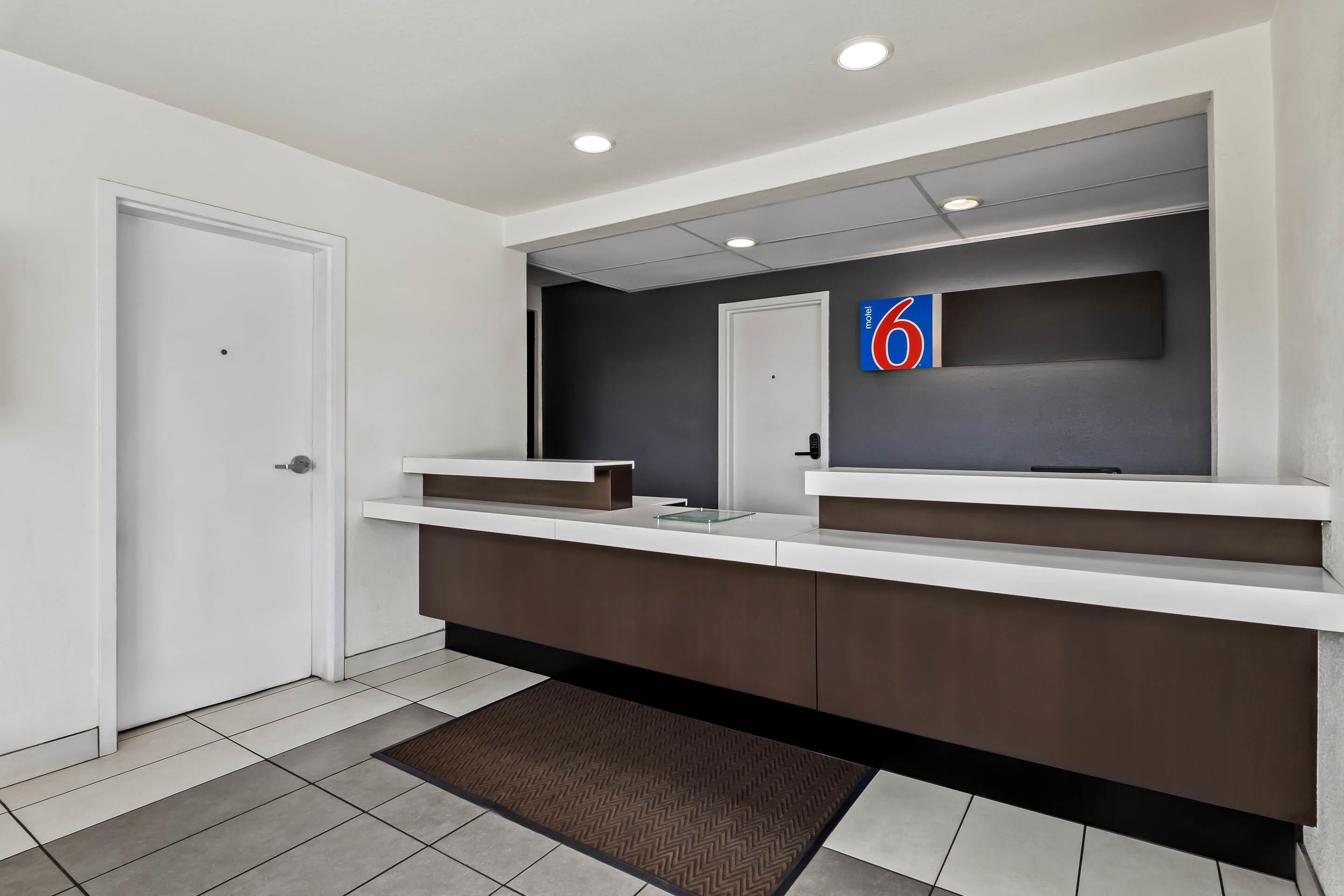A modern reception area with a large mirror, a reception desk, and a door.