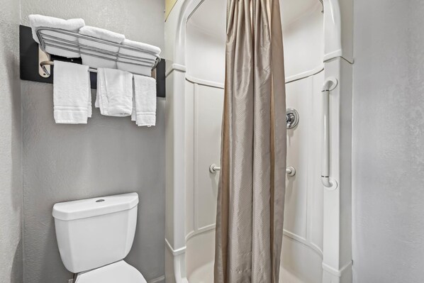 A modern bathroom with a toilet, a towel rack with folded towels, and a shower enclosure.