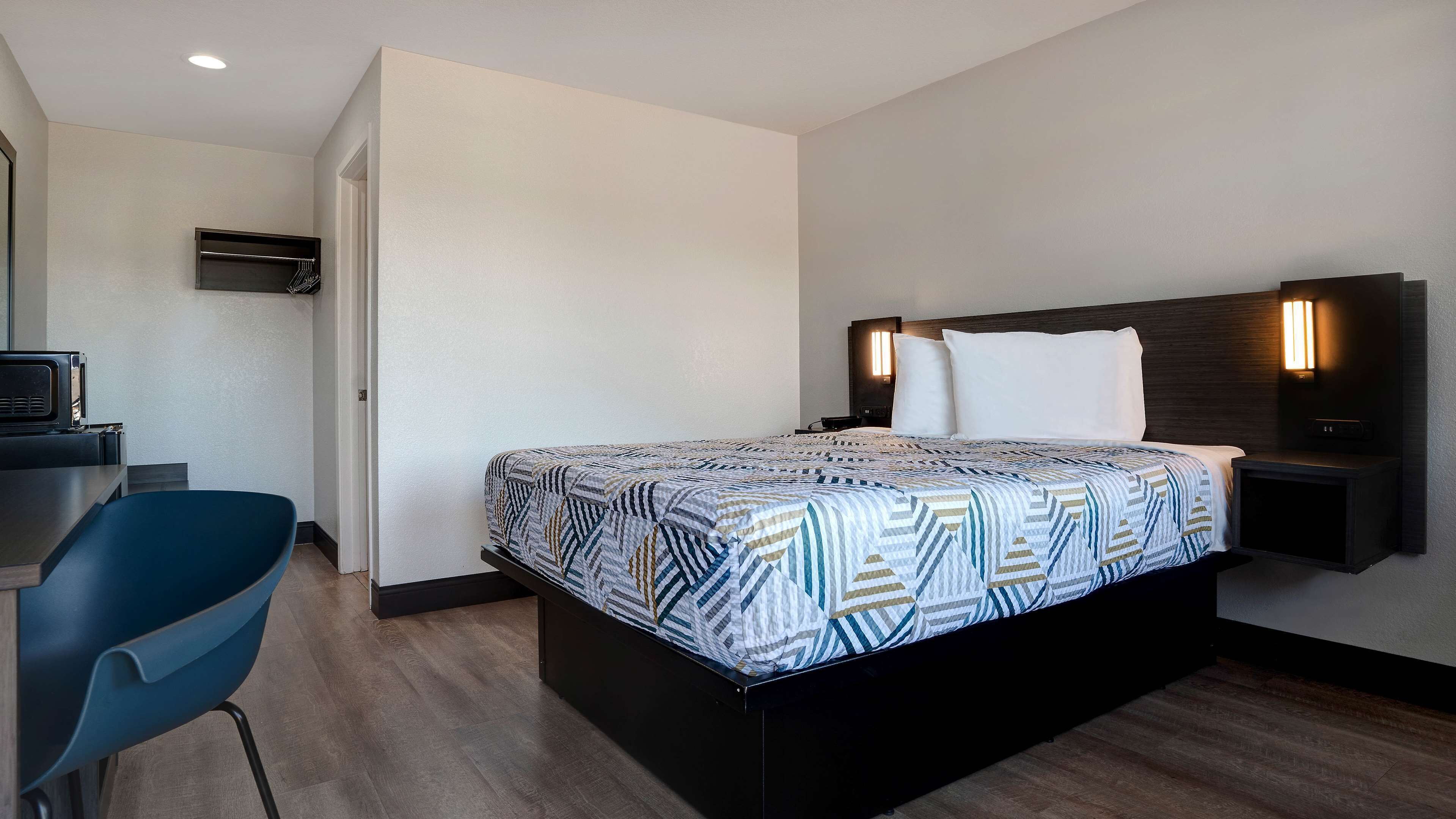 A hotel room with a bed, a desk, and a chair.