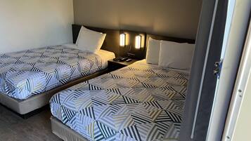 Two single beds with geometric patterned bedding, bedside tables with lamps, and a wooden headboard.