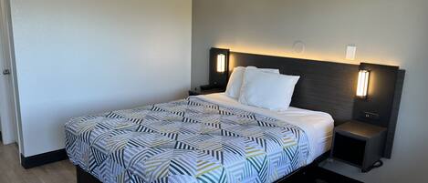 Un hotel moderno con una cama grande, una mesita de noche y una mesilla.