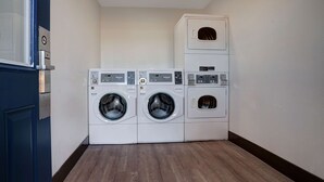 A laundry room with two front-loading washers and a stacked dryer. - Motel 6 Arcata, CA - Cal Poly Humboldt (Arcata)
