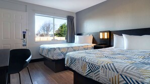 A hotel room with two beds, a desk, a chair, a window with a view, and a door with a keycard reader. - Motel 6 Arcata, CA - Cal Poly Humboldt (Arcata)