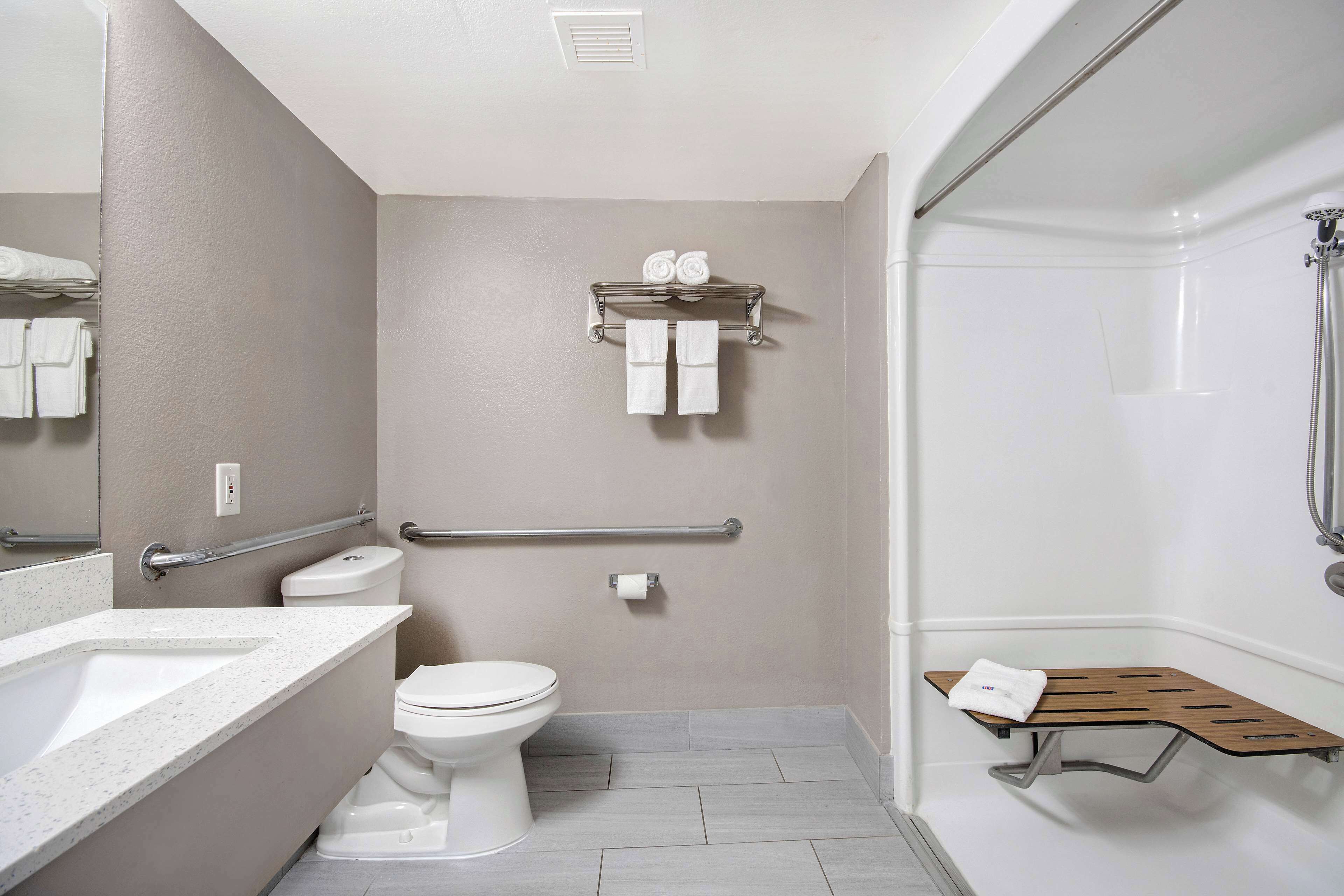 Ein modernes Badezimmer mit Toilette, Waschbecken, Dusche und Handtuchhalter.