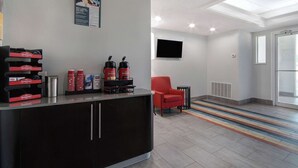 Een receptiebalie met een zwarte toonbank, rode stoelen en een flatscreen televisie aan de muur.