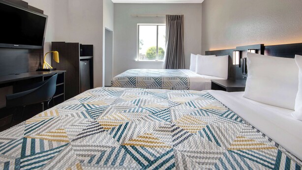 Een hotelkamer met een groot bed, een bureau met een televisie en een raam met gordijnen.
