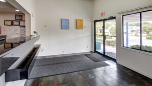 A clean, modern lobby with a reception desk, a set of stairs, and a large glass door leading outside.