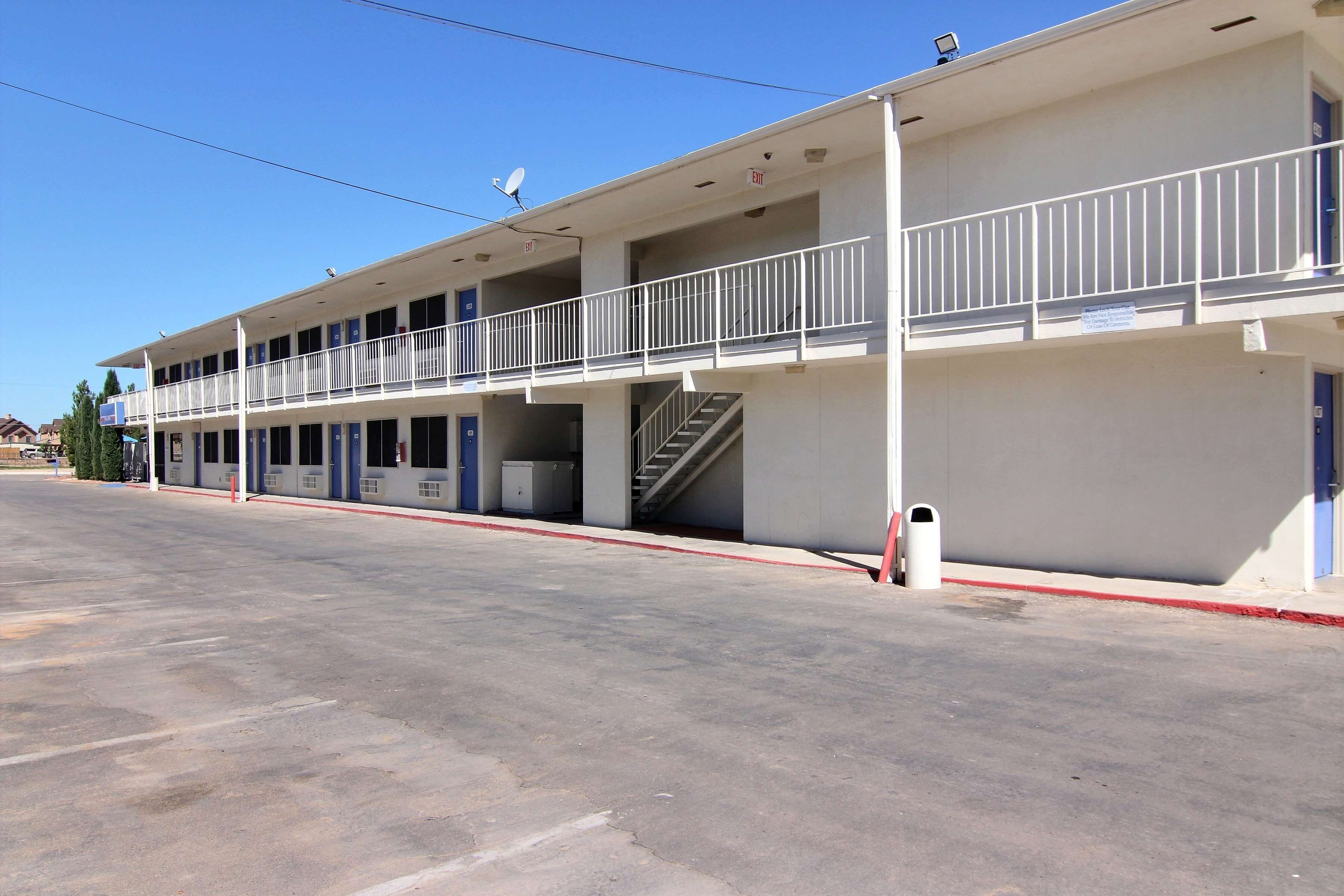 A two-story motel with a central staircase, a flat roof, and a parking lot.