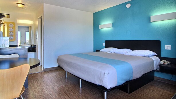 Ein modernes Hotelzimmer mit Bett, Nachttisch und Schreibtisch mit Stuhl.