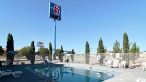 Ein Poolbereich mit Liegestühlen, einem Schild für Motel 6 und einem umzäunten Bereich.