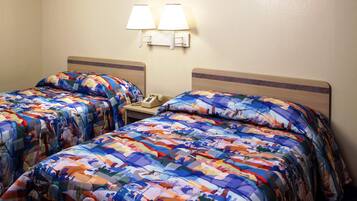 A hotel room with two beds, each with a colorful quilt, a bedside table with a lamp, and a telephone.