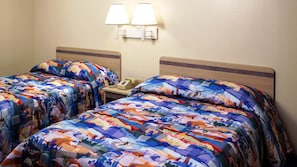 A hotel room with two beds, each with a colorful quilt, a bedside table with a lamp, and a telephone. - Motel 6 Beatty, NV - Death Valley (Beatty)