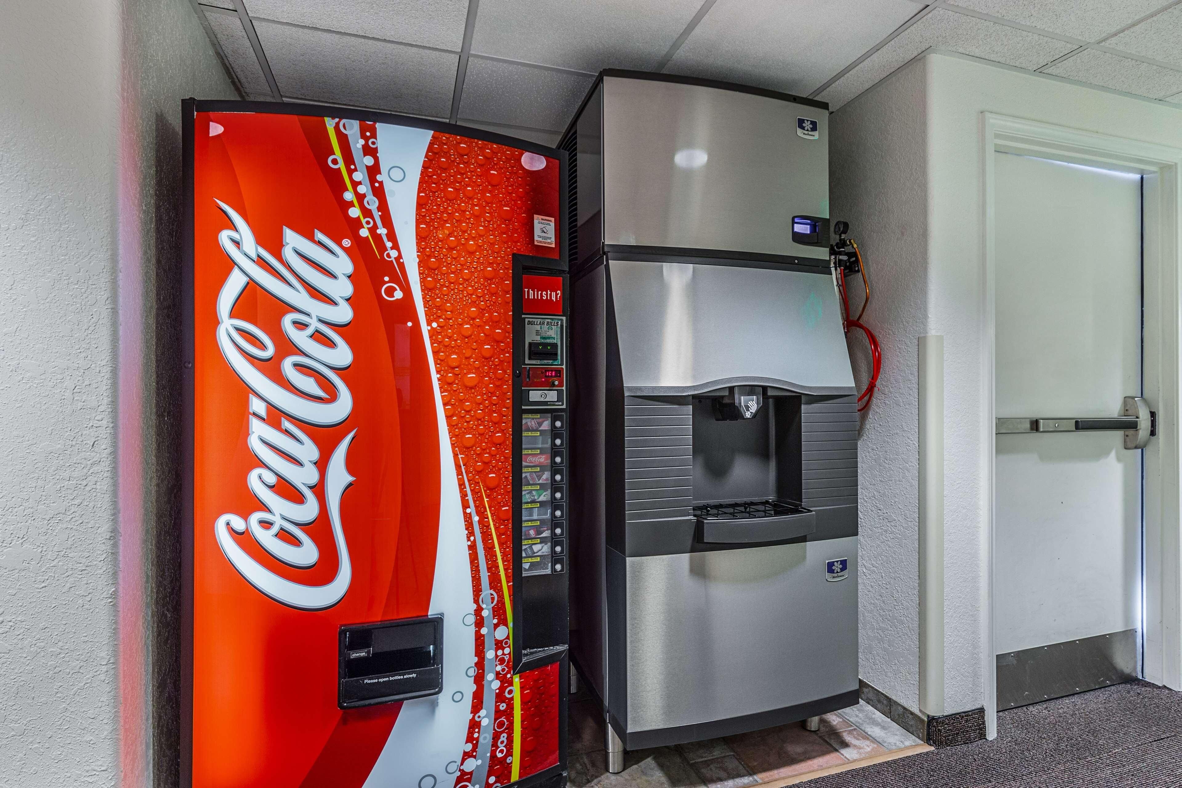 Un distributeur automatique de Coca-Cola et un réfrigérateur en acier inoxydable dans un couloir.