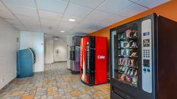 A corridor with vending machines, a refrigerator, and a Coca-Cola branded refrigerator.